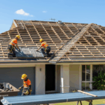 Roofers removing old roofing materials from a home and preparing for a new Colorbond installation under clear skies.