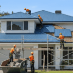 Roofing professionals installing new Colorbond panels on a home under clear skies, representing a quality roof replacement in progress.